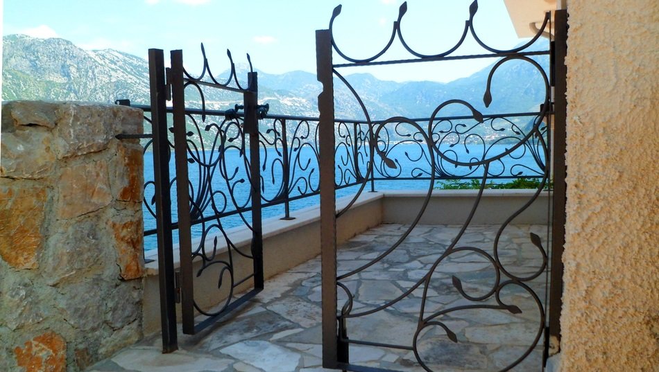 terrace with wrought iron fence in view of sea and mountains