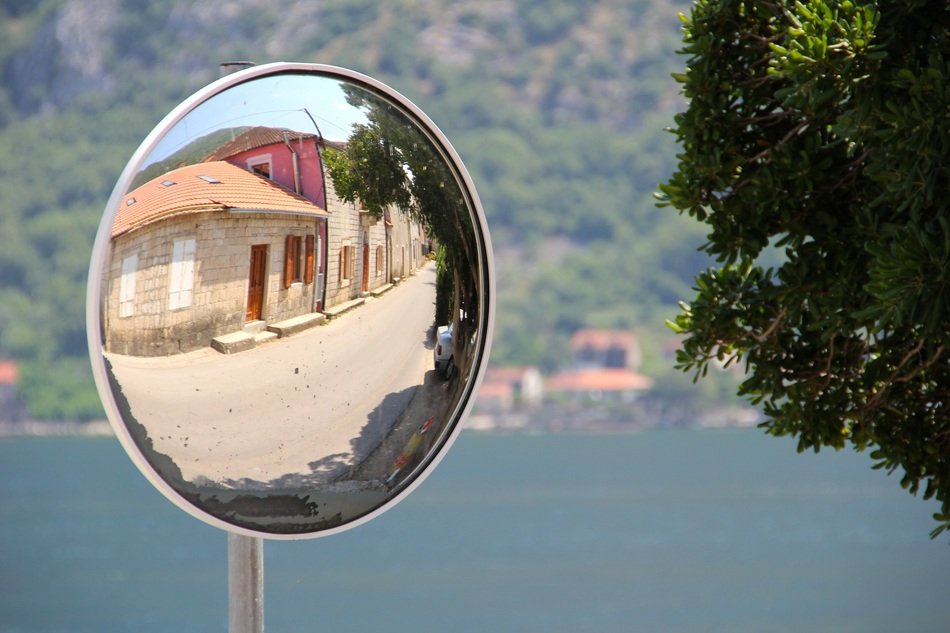 reflection of a village in a vehicle mirror
