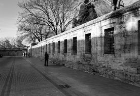 black and white photo of a man near an old house with the trees along in Istanbul, Turkey