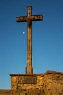 old wooden cross on stone wall at sky