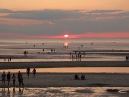 Landscape of the people are on a beach at the sunset