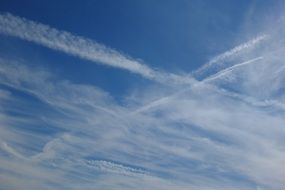 White vapour trails and clouds in the blue sky