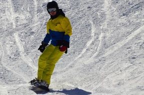 snowboarder in a yellow-blue suit on a snowy mountain