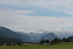 distant view of a church in a village at the foot of the mountains