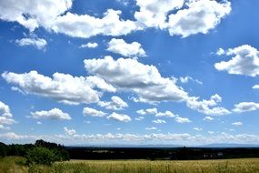 cumulus clouds in blue sky above summer countryside