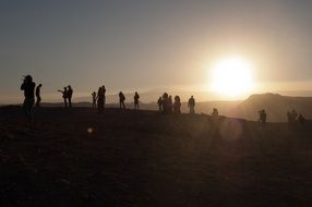 silhouettes of many people in the mountains at sunset