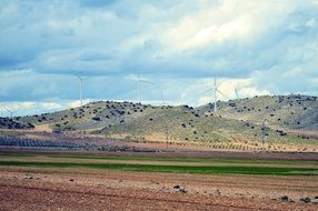 wind turbines on a hill above a field with colorful nature in Spain