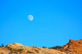 Beautiful Moon in the blue sky above the colorful rocks