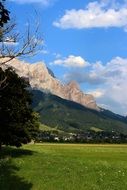 landscape of green meadow at the foot of mountains