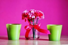 green candles and artificial flowers at purple background, still life