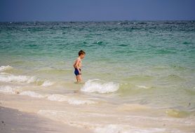 child on tropical beach in thailand on a sunny day