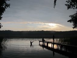 man in a lake at colorful sunset in Trzebiechowo, Poland