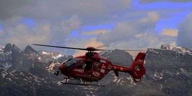 red rescue helicopter over the mountains