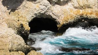 Sea Waves splashing on Rocky Coast at cave opening, cyprus, ayia napa
