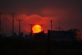 fiery sun and red sunset over power lines