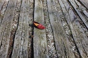 lost red shoe on a wooden deck