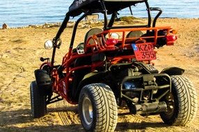 red buggy stands in the sand