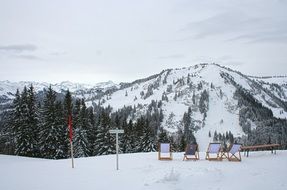 Landscape of deck chairs on a snow covered alpine mountain top