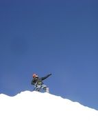 climber on top of a snowy mountain against a blue sky