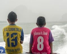 two boys in sports uniforms on the coast