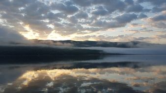 cloudy sky at sunrise reflected in water