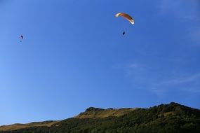 paragliders fly over the hills