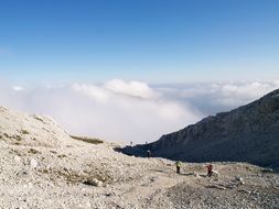 hikers on Mountain slope at clouds