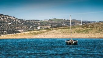 lonely sailboat on the shore of a blue lake