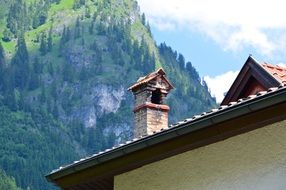 Beautiful, picturesque and Chimney Roof near the beautiful, green mountain with trees