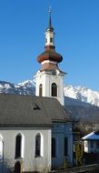photo of a white church on a background of snowy mountains in Tyrol, Austria