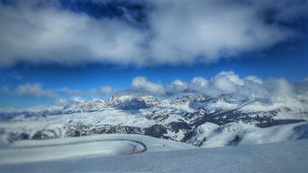 Panorama of the beautiful snowy Dolomite mountains under blue sky with white clouds in Italy