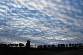 white clouds in the sky above the field at dusk