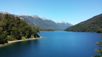 green forest and snow-capped Mountains at Lake, summer Landscape