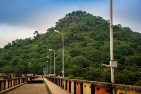 footbridge with lampposts near the green mountain