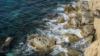ocean foam by the rocky coast in cape greco