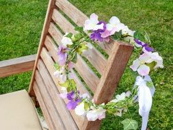 Beautiful and colorful wreath on wooden armchair among the green grass
