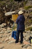Man is painting on the rocks on the beach
