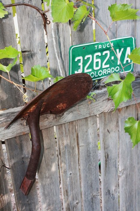 rusty shovel and license plate on a wooden fence
