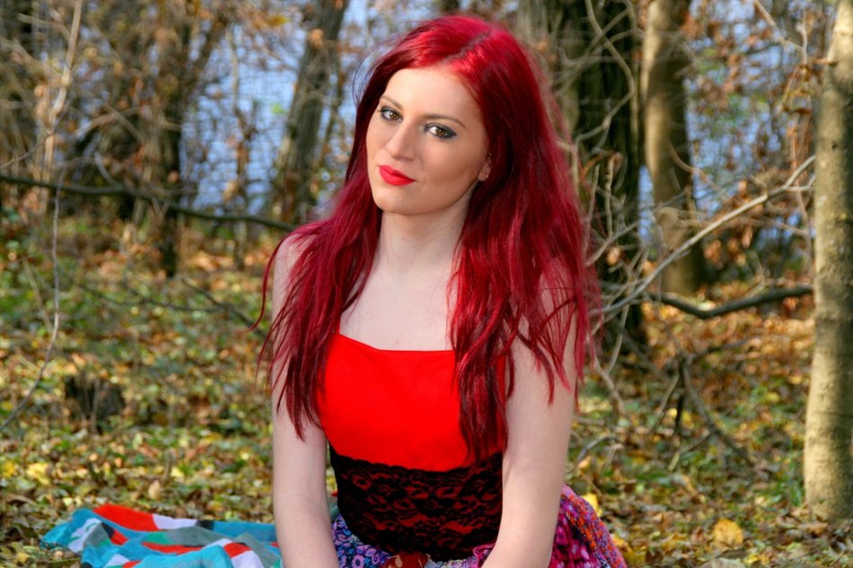 girl with red hair and in a bright dress in the forest