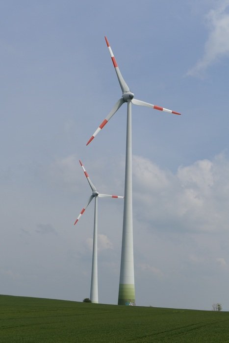 two Wind turbins on green hill at sky background with white clouds