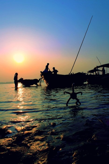 fishermen on boats by the river at sunset in bengal