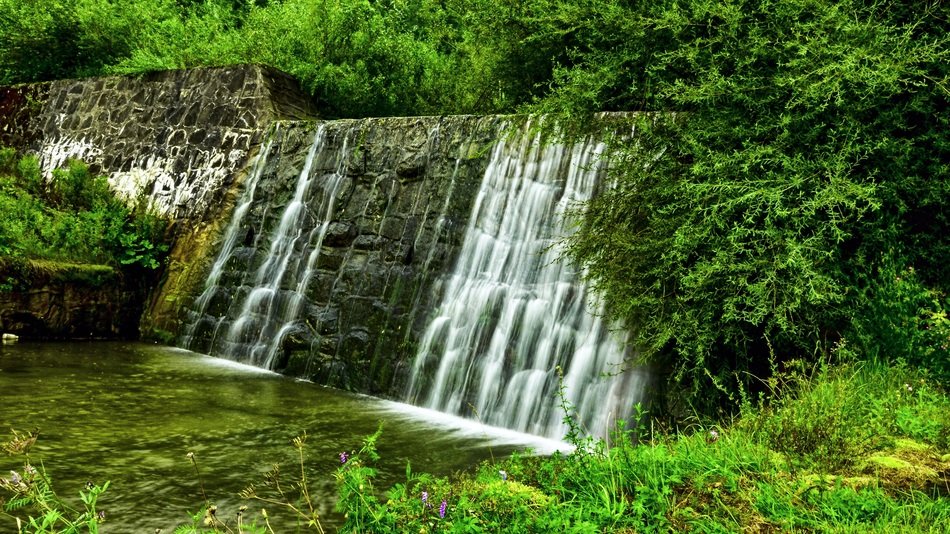 water falls from aged stone dam at summer, Poland, Malopolska, Łukowica