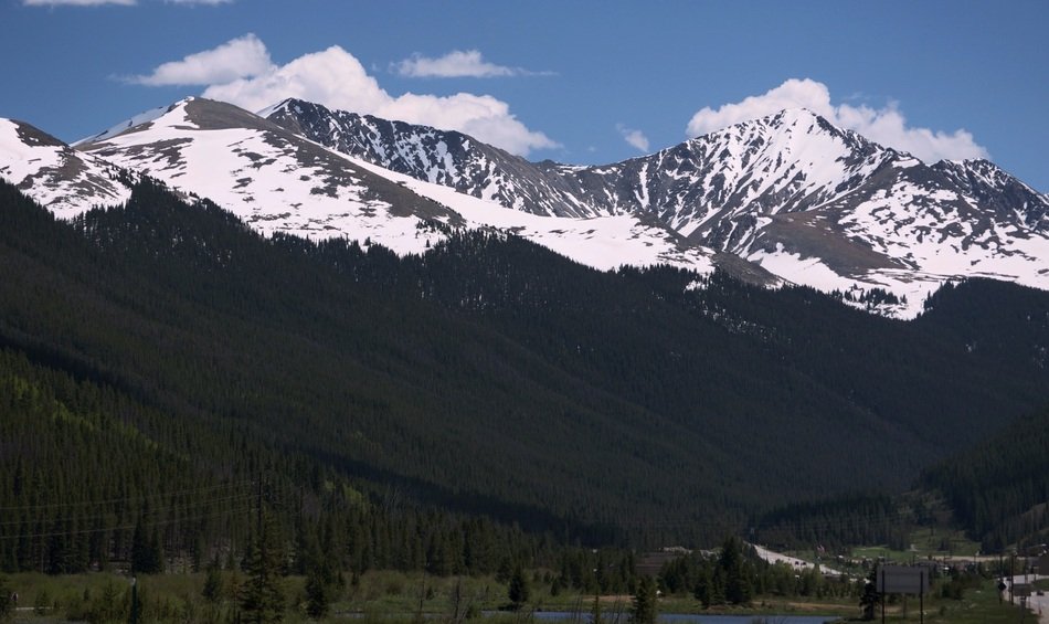 mountain peaks in the snow behind green hills