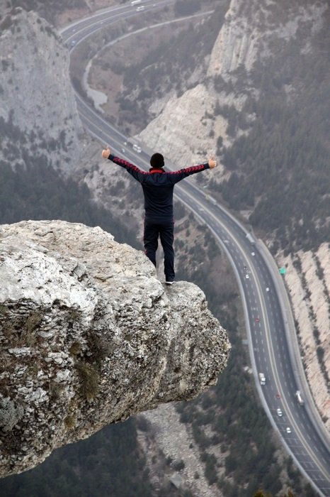 young man stands on Cliff above winding road, Freedom