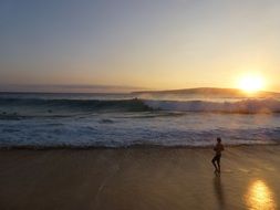 person looking at stormy sea from wet sand beach