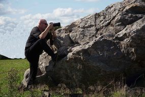 a man makes a photo near a stone on a sunny day