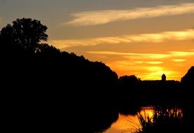 silhouette of the castle by the river and forest