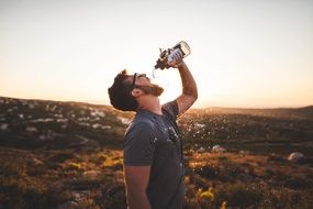 man drinking in the mountains