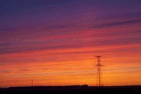 distant power line with mast at colorful Sunset Sky