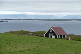 chapel on a green meadow near the water in iceland
